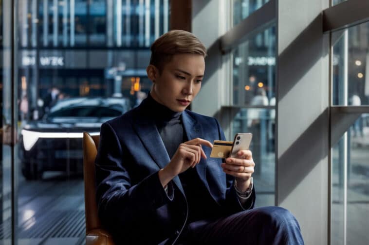 Un client consulte son appli bancaire avec une carte Gold en main